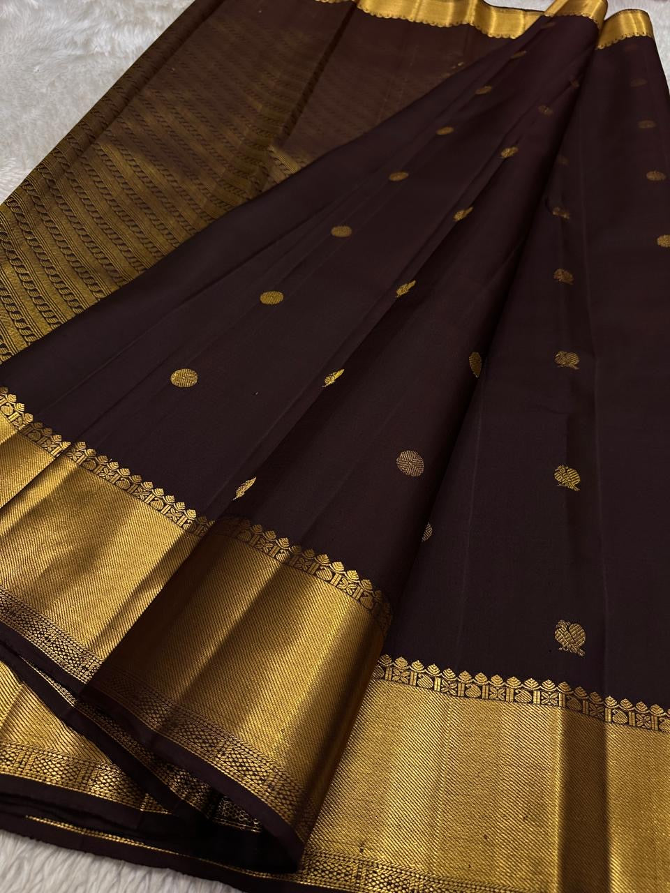 Agnika – Dark Espresso Kanchipuram Silk Saree with Mayil Chakram Butta
Fiery and regal, Agnika features a rich dark espresso silk body with intricate Mayil Chakram (peacock) motifs and a shimmering zari border—an elegant ode to South Indian tradition.