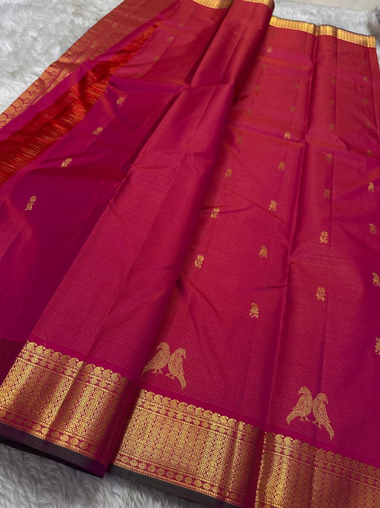 Rani Kili Butta Vairaoosi — Pure Silk Kanchipuram Saree
Rani-pink body with zari buttas & twin parrot motifs, antique-gold coin borders with emerald selvedge
Rich red-orange vairaoosi pallu with rosette brocade, matching blouse included
Silk Mark Cert
