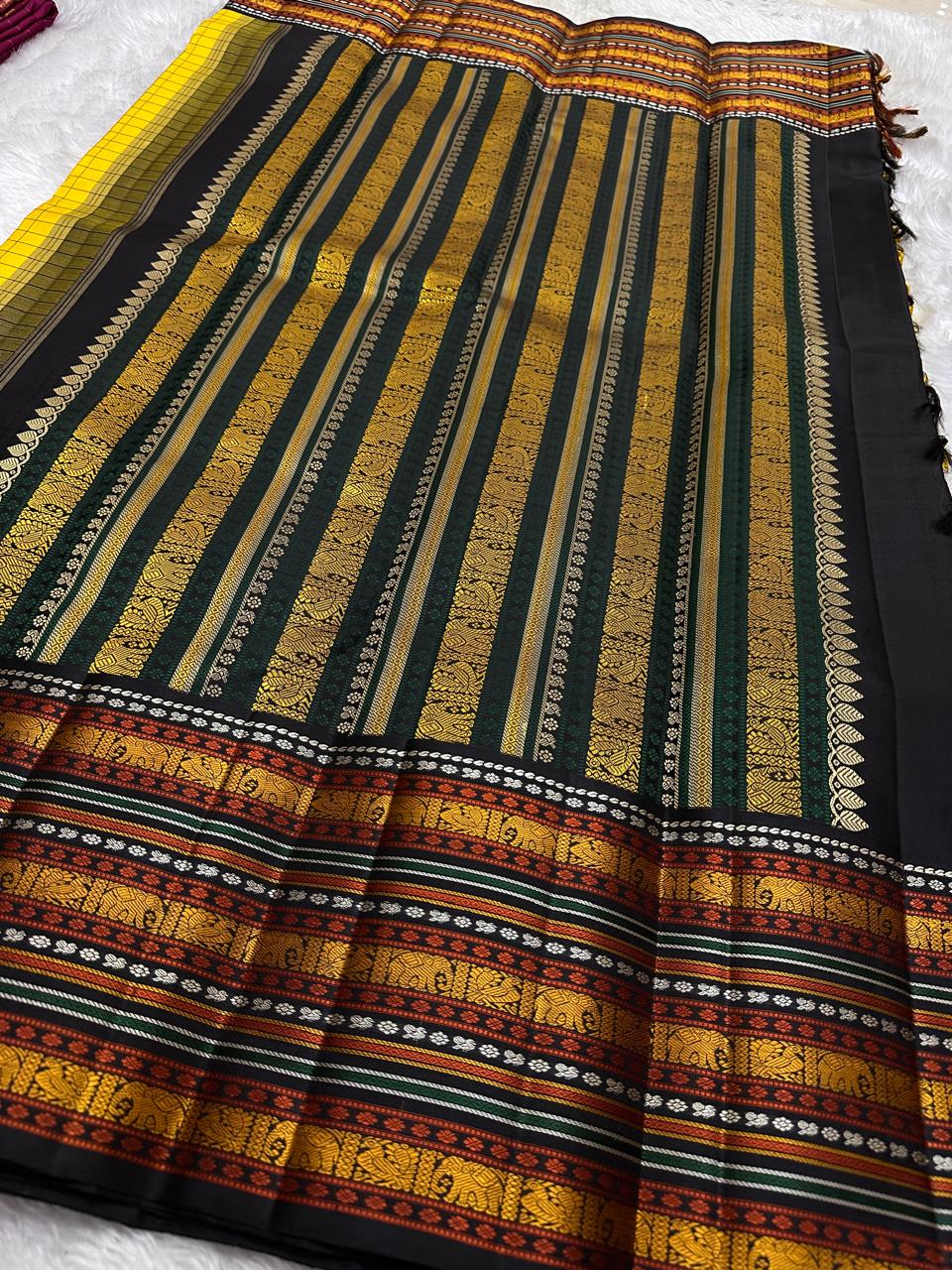 Marigold Mani Kattam – Pure Kanchipuram Silk Saree
Vibrant marigold yellow body with classic kattam checks
black borders with elephant & floral zari motifs
Rich black pallu adorned with green & zari stripes . Silk Mark Certified, delivery in 2 weeks