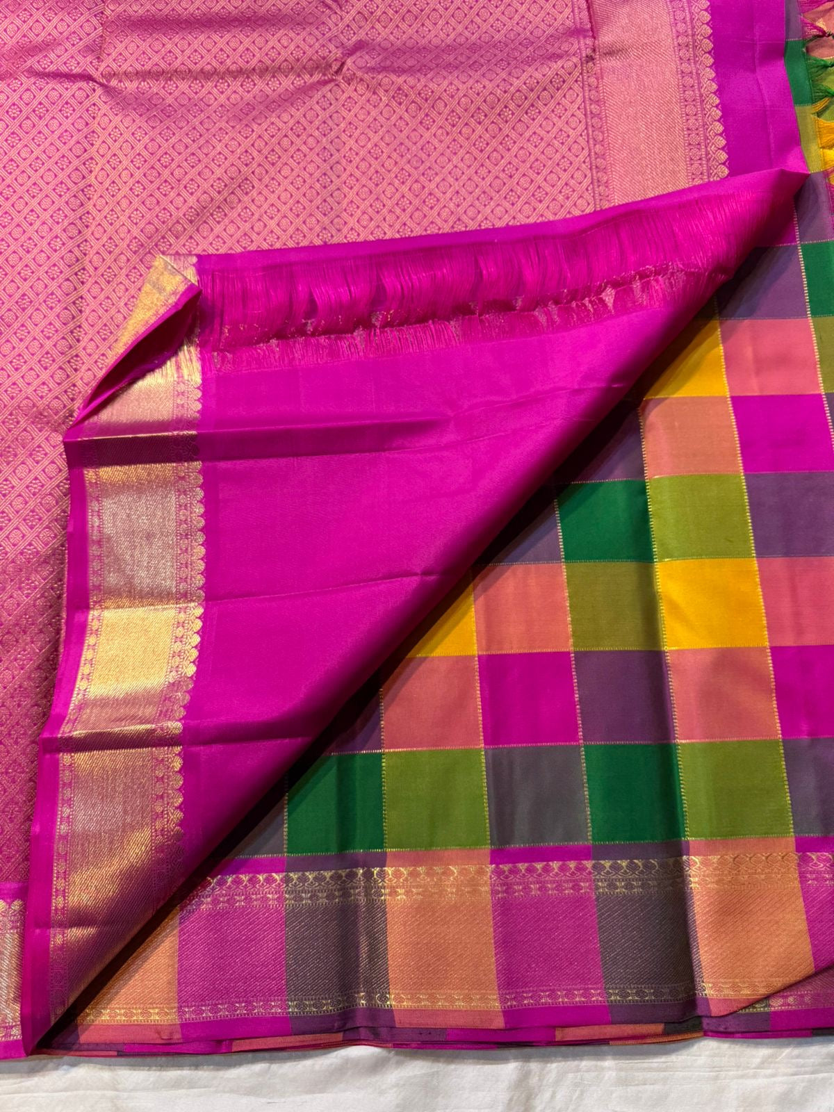 Pallavi – Kanchipuram Paalum pazhamum checks/ Zari kattam Silk Saree in Turmeric, Mango, Leaf Green & Beetroot Pink Checks.
Finished with a vibrant magenta border and rich gold zari pallu.