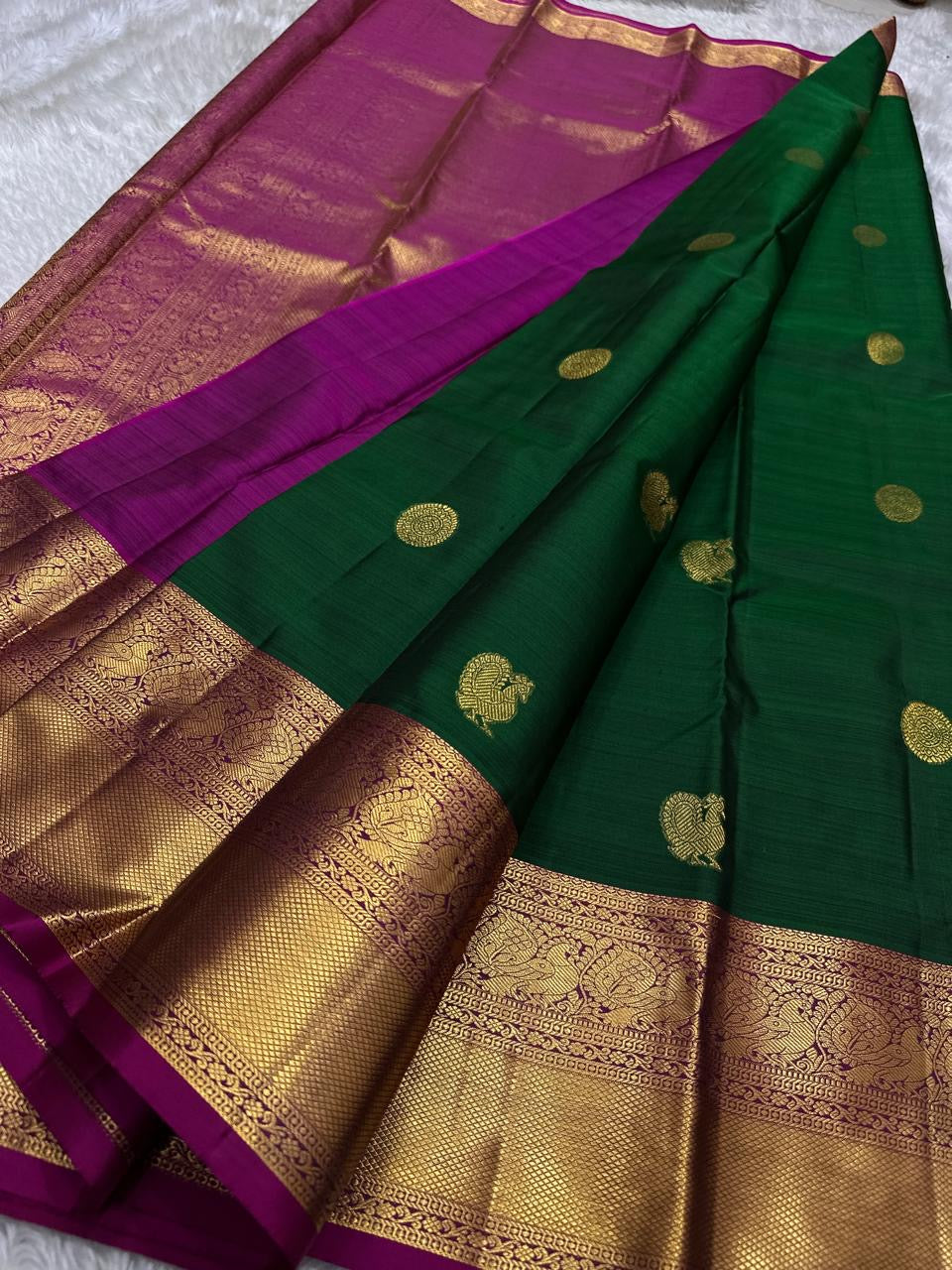 Maragatha Mayil Butta — Kanchipuram Pure Silk
Emerald green (maragatham) body with gold mayil/peacock buttas
Contrast rani-magenta korvai borders & zari-rich pallu
Silk Mark Certified | Free Shipping within USA