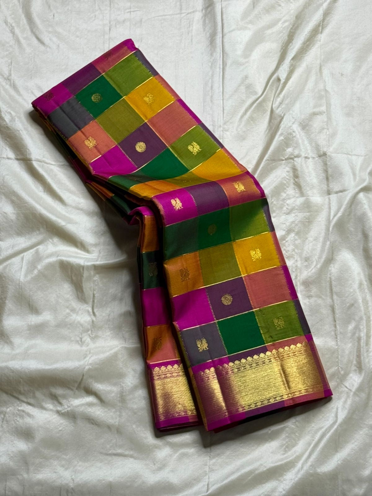 Pallavi – Kanchipuram Paalum pazhamum checks/ Zari kattam Silk Saree in Turmeric, Mango, Leaf Green & Beetroot Pink Checks.
Finished with a vibrant magenta border and rich gold zari pallu.