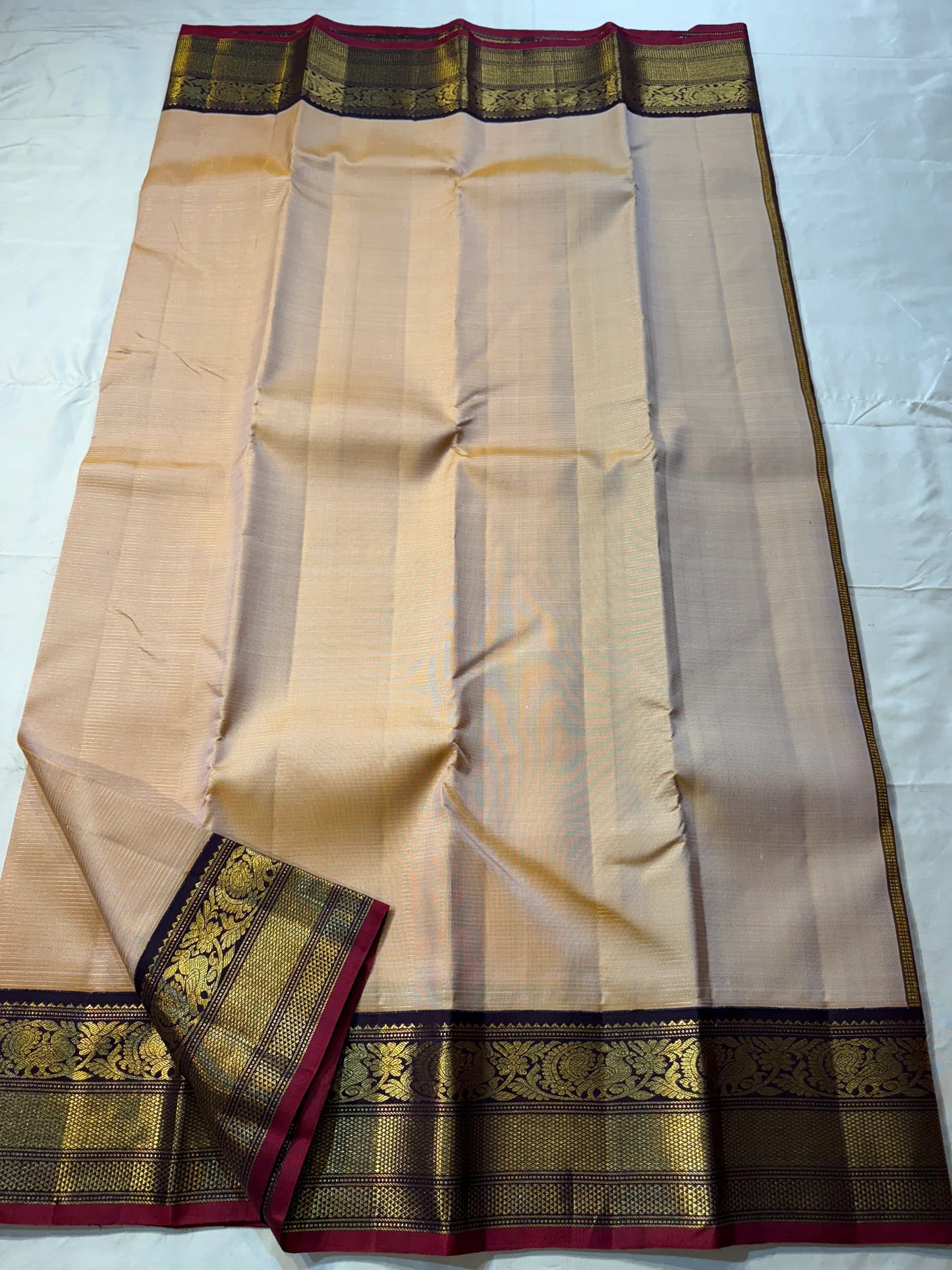 Sandhya ๐
โ Sun-Kissed Beige Kanchipuram Silk Saree with Subtle Vairaoosi Gold Filament โจ, Deep Purple Peacock Diamond-Pettu Zari Border ๐ฆ, Deep Maroon Selvedge, and Zari-Embellished Pallu with Arai Maadam & Khalasam Motifs ๐ฟ๐