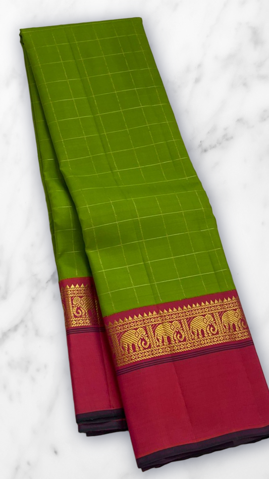 Valli Pachai – Kanchipuram Pure Silk Saree
Parrot-green body in kattam (grid) checks with subtle zari lines
Korvai contrast rani-pink borders featuring gaja (elephant) procession & temple reku motifs
Rich rani-pink zari pallu with vertical bands