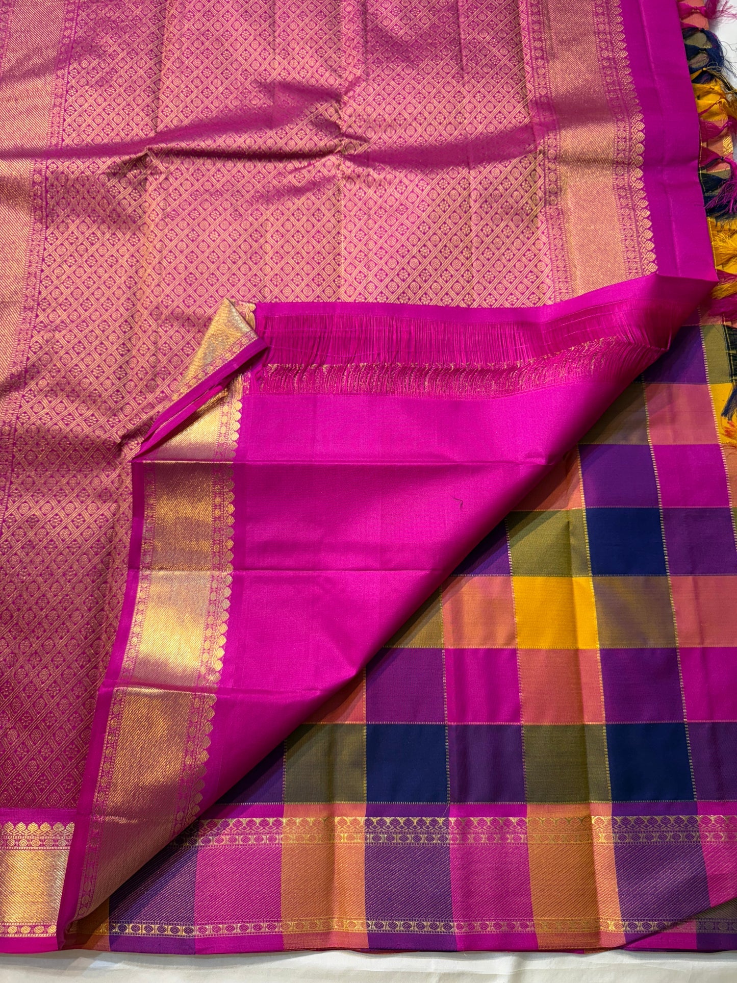 Navaranga Kattam — Multi-Color Paalum pazhamum checks  Kanchipuram Pure Silk
Rani-magenta contrast border & rich zari pallū 
Gold coin & peacock buttas over jewel-tone squares
Handloom Kanchipuram • Matching magenta blouse with borders