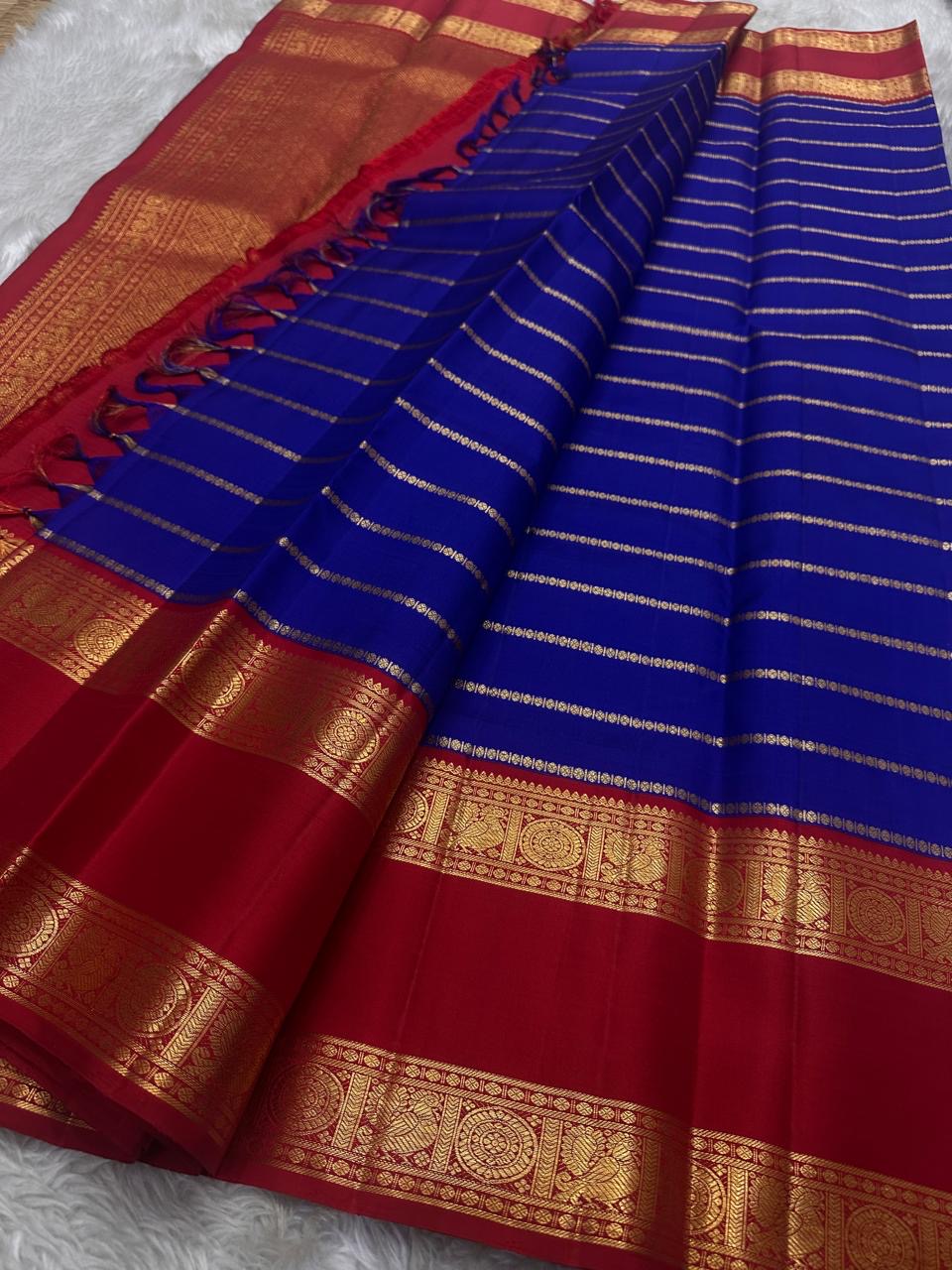 Meera – A Living Raga in Kanchipuram Silk: Draped in Crimson and Iconic MS Blue, Adorned with Gold Zari Seer, Muthu Borders, and Peacocks and kamalam , Woven in the Spirit of Classical Grace and Devotion