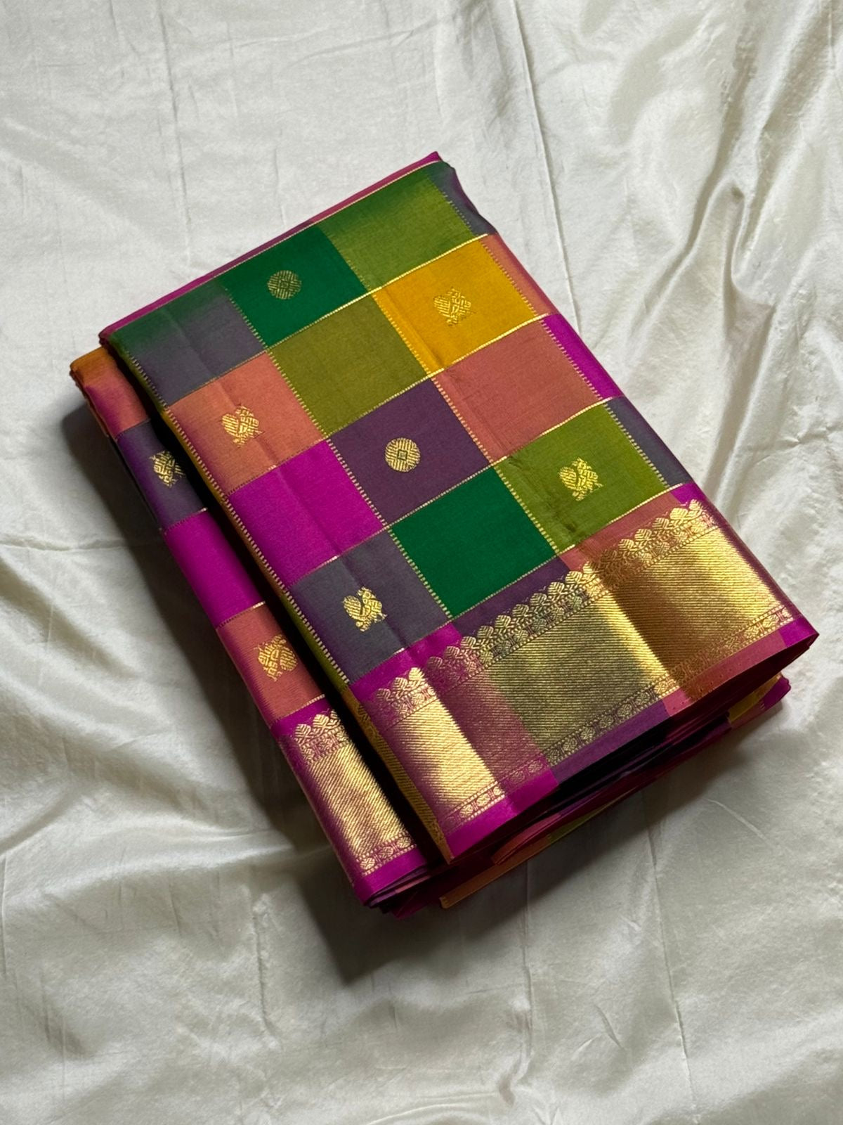 Pallavi – Kanchipuram Paalum pazhamum checks/ Zari kattam Silk Saree in Turmeric, Mango, Leaf Green & Beetroot Pink Checks.
Finished with a vibrant magenta border and rich gold zari pallu.