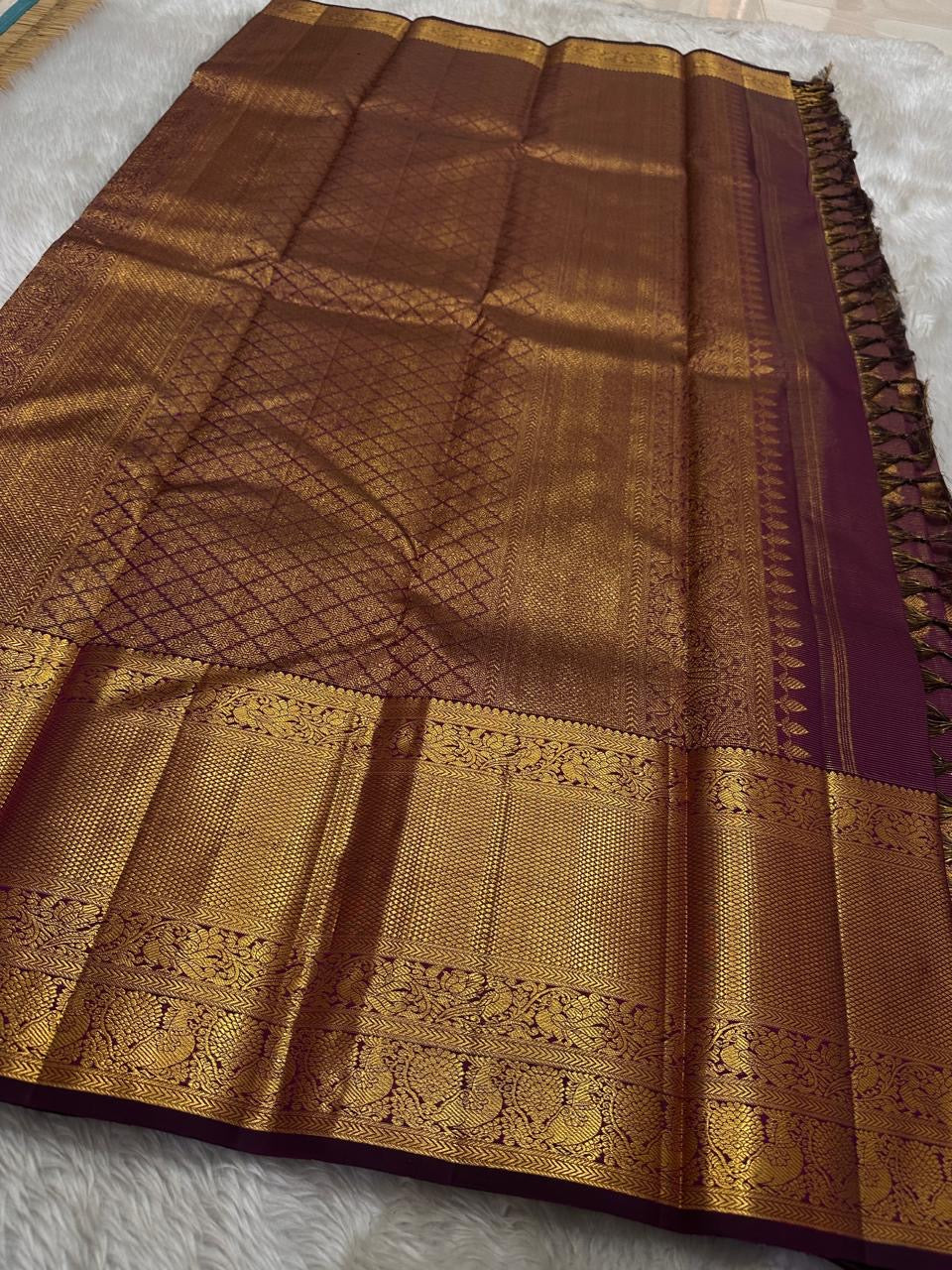 Varnika – Handwoven Kanchipuram Silk Saree in Plum Wine
A regal plum Kanchipuram silk saree adorned with gold zari paisleys and Gandaberunda motifs