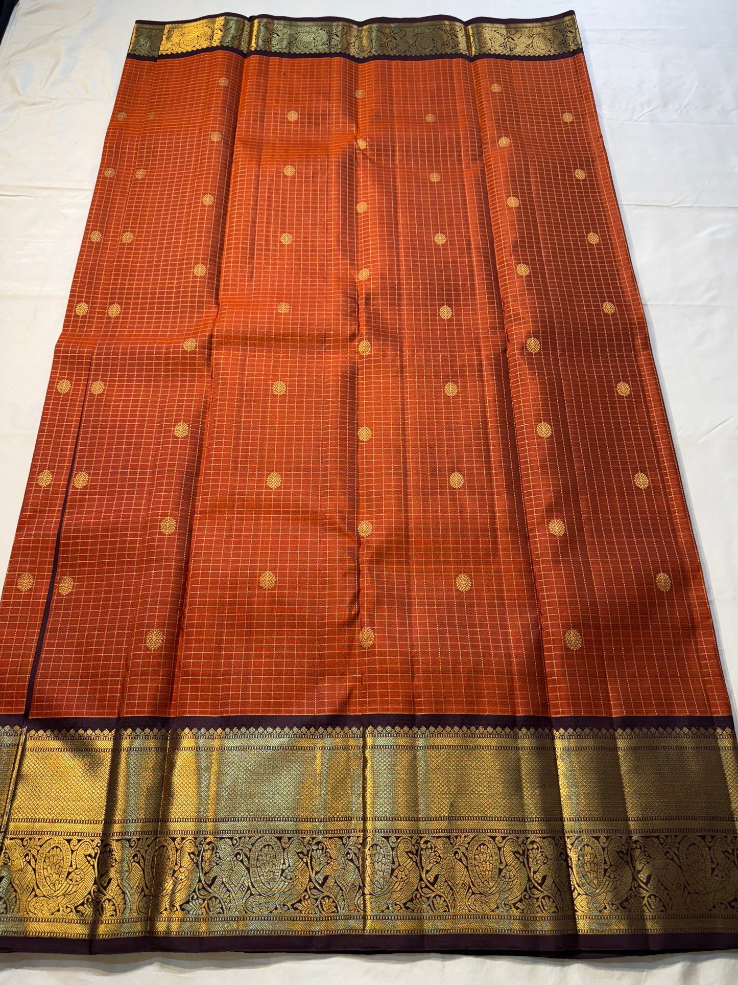 Rust Orange Kattam & Purple Korvai – Pure Kanchipuram Silk Saree
Rust-orange checks with delicate gold buttas and contrast purple korvai borders
Grand purple zari-pallu | Contrast purple blouse | Fall & Pico Done
Silk mark certified ships