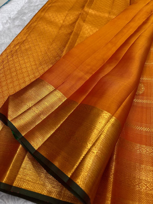Handwoven Kanchipuram Veldhari saree in shot amber golden orange with green selvedge, Zari Kattam grid, and Maanga Butta, full folded view