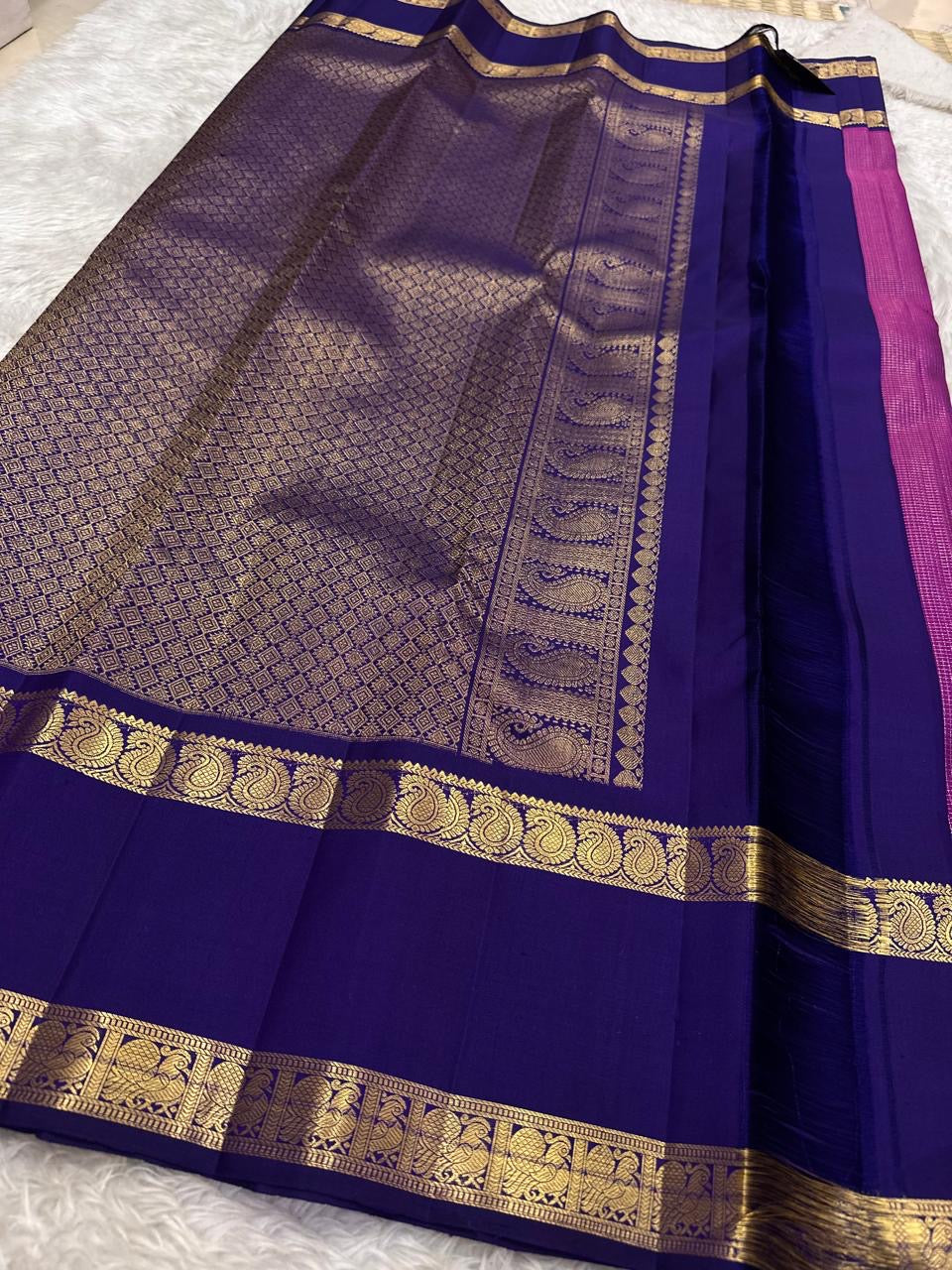 Folded view of magenta and violet handwoven pure silk Kanchi Pattu saree with Zari Kattam body and Rettapet Paisley Peacock border