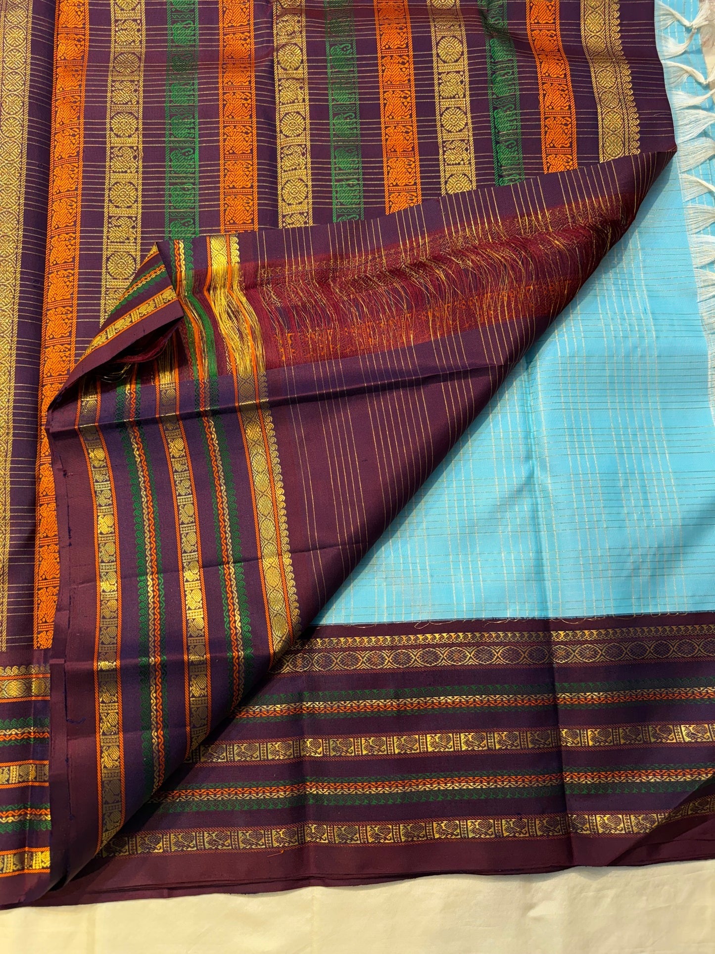 Deep maroon pallu with dense gold zari woven motifs — full spread