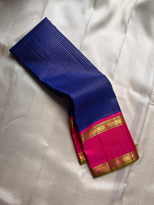 Pure Kanchipuram silk saree draped showing blue checked body, contrasting pink zari border, and blue tassels along the edge