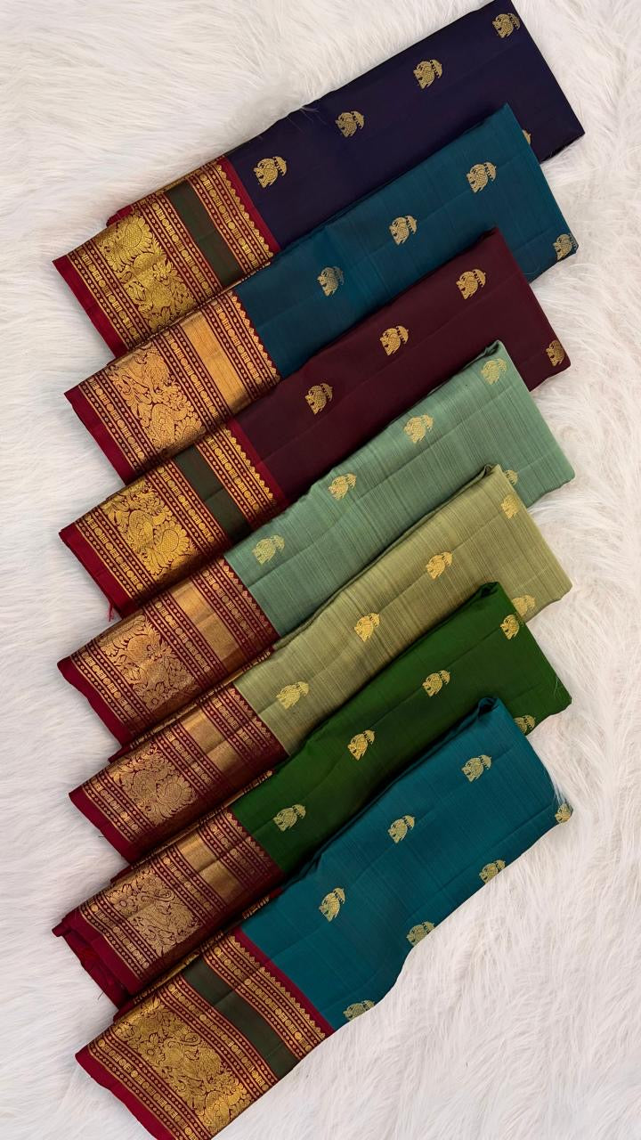 Folded bottle green Kanchi Pattu pure silk saree showing Yaanai Ambari Butta body and deep red Vanasringaram border