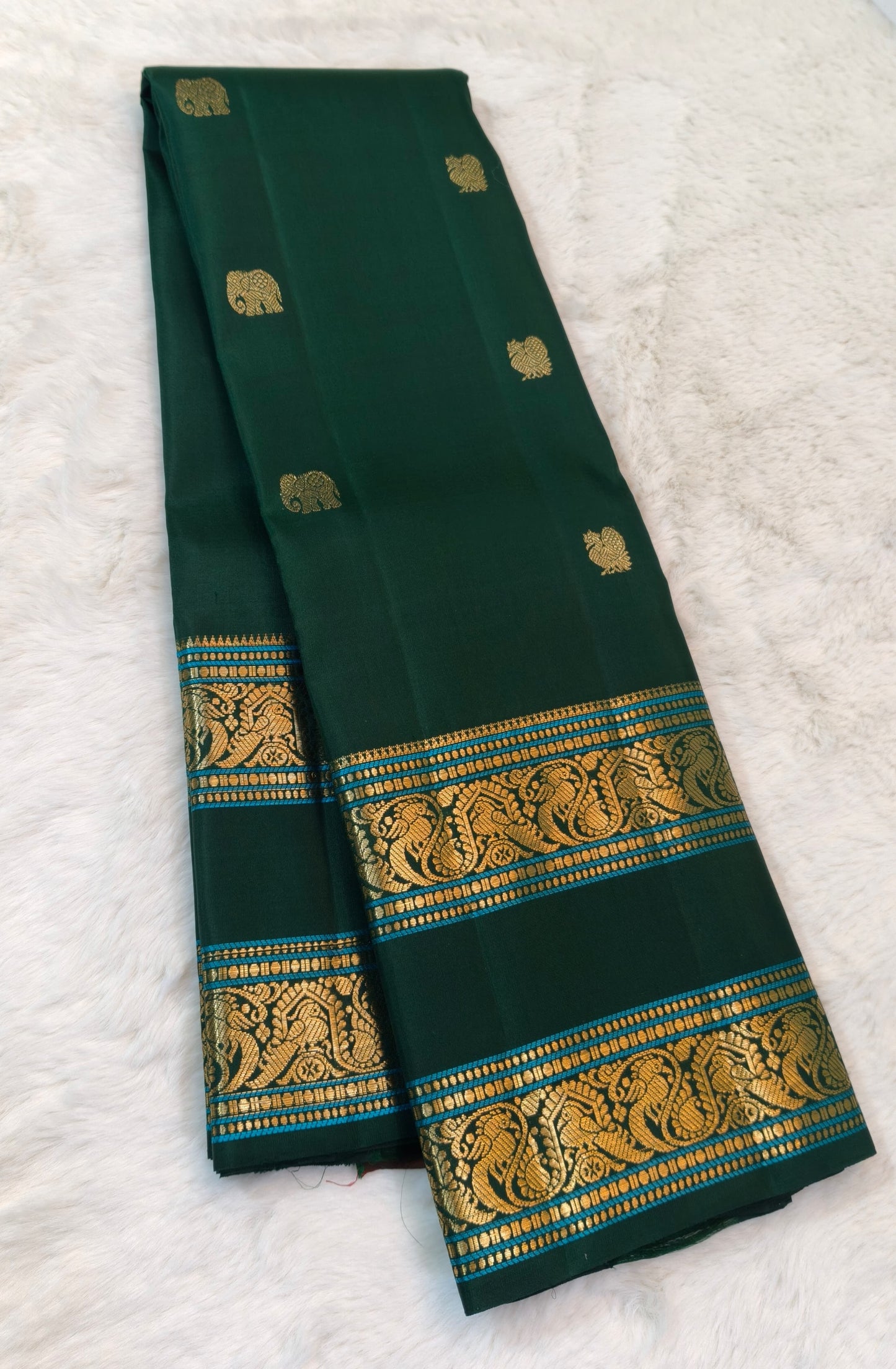 Bottle green handwoven Kanchipuram silk saree showing its traditional Rettapet zari borders.