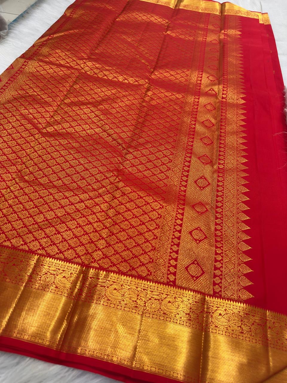 Gold zari peacock and floral detail along the border of bright red Kanchipuram silk