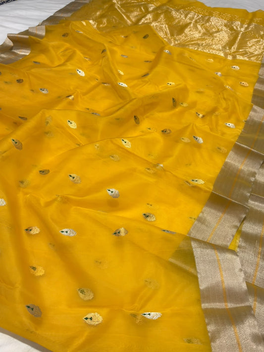 Turmeric yellow Chanderi saree showing scattered pale metallic buttas with green accents and silver-toned border