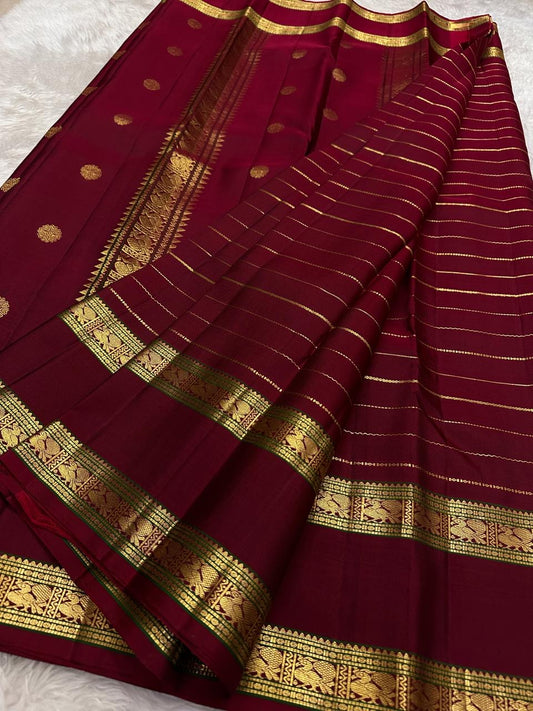 Close view of framed Mayil motifs woven in warm gold zari on Deep Arakku Red border.