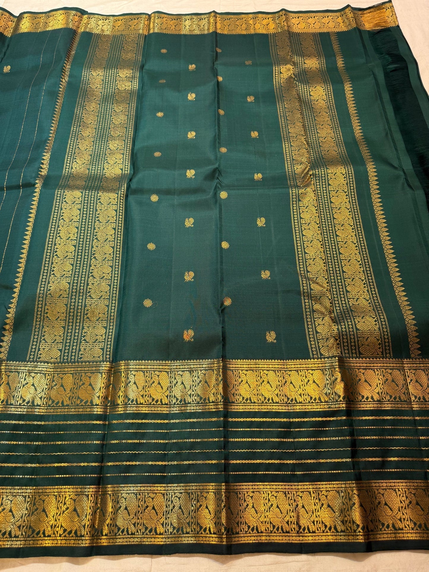 Traditional warm gold Varisaipet registers woven against deep green Kanchipuram silk.