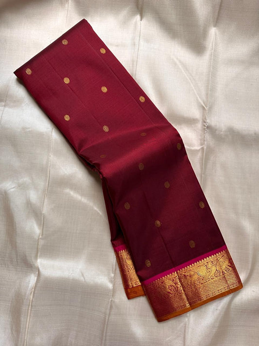 Deep red silk saree draped lengthwise showing scattered gold buttas and broad zari woven border.