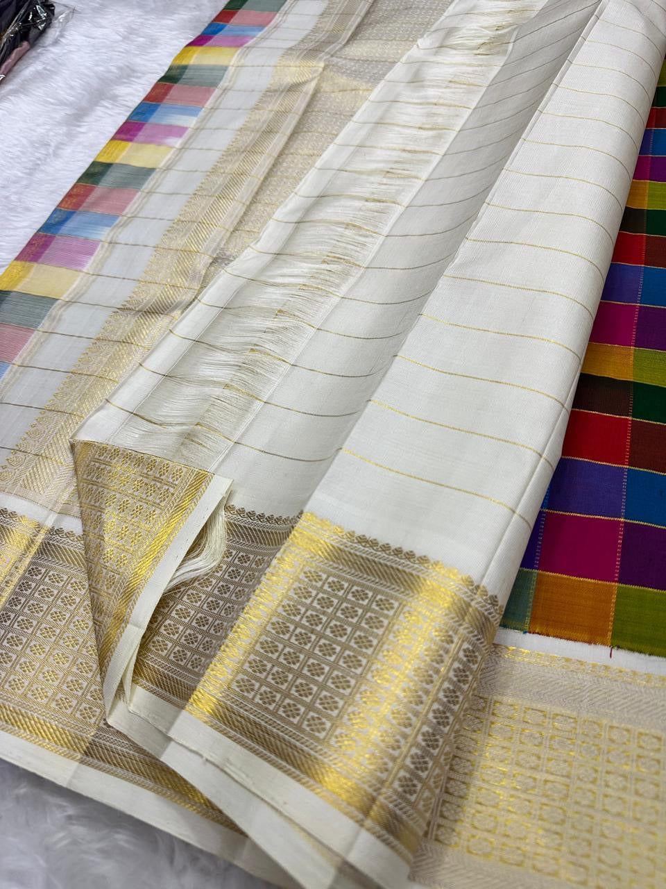 Angled fold view of a multicolour Paalum Pazhamum Kanchipuram silk saree with ivory body and antique gold zari border