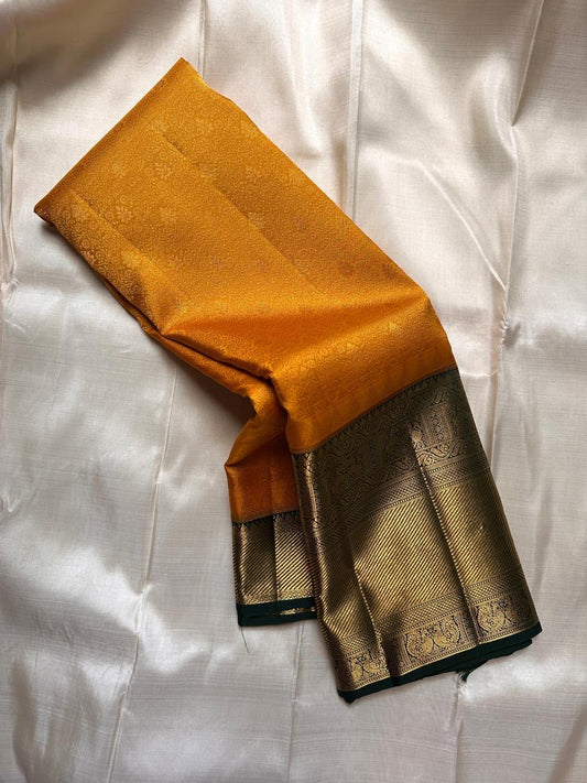 Mustard yellow Pure Kanchipuram silk saree draped to show dark green edge and wide zari woven gold border.