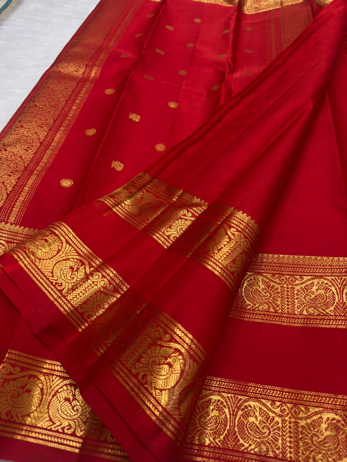 Gold zari buttas on the vermilion red KanchiPattu Rettapet saree, Yazhi border detail