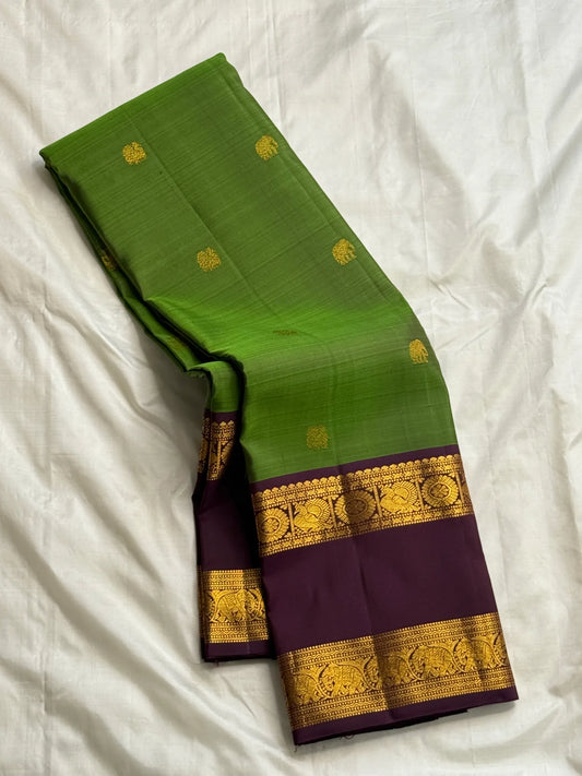 Green Pure Kanchipuram silk saree folded with broad purple contrast border and gold zari woven elephant detailing