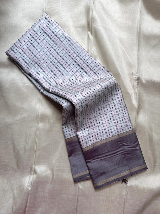 Close view of pure Kanchipuram silk saree showing soft grey silk border with classic gold zari stripes and a richly woven pallu in antique gold zari.