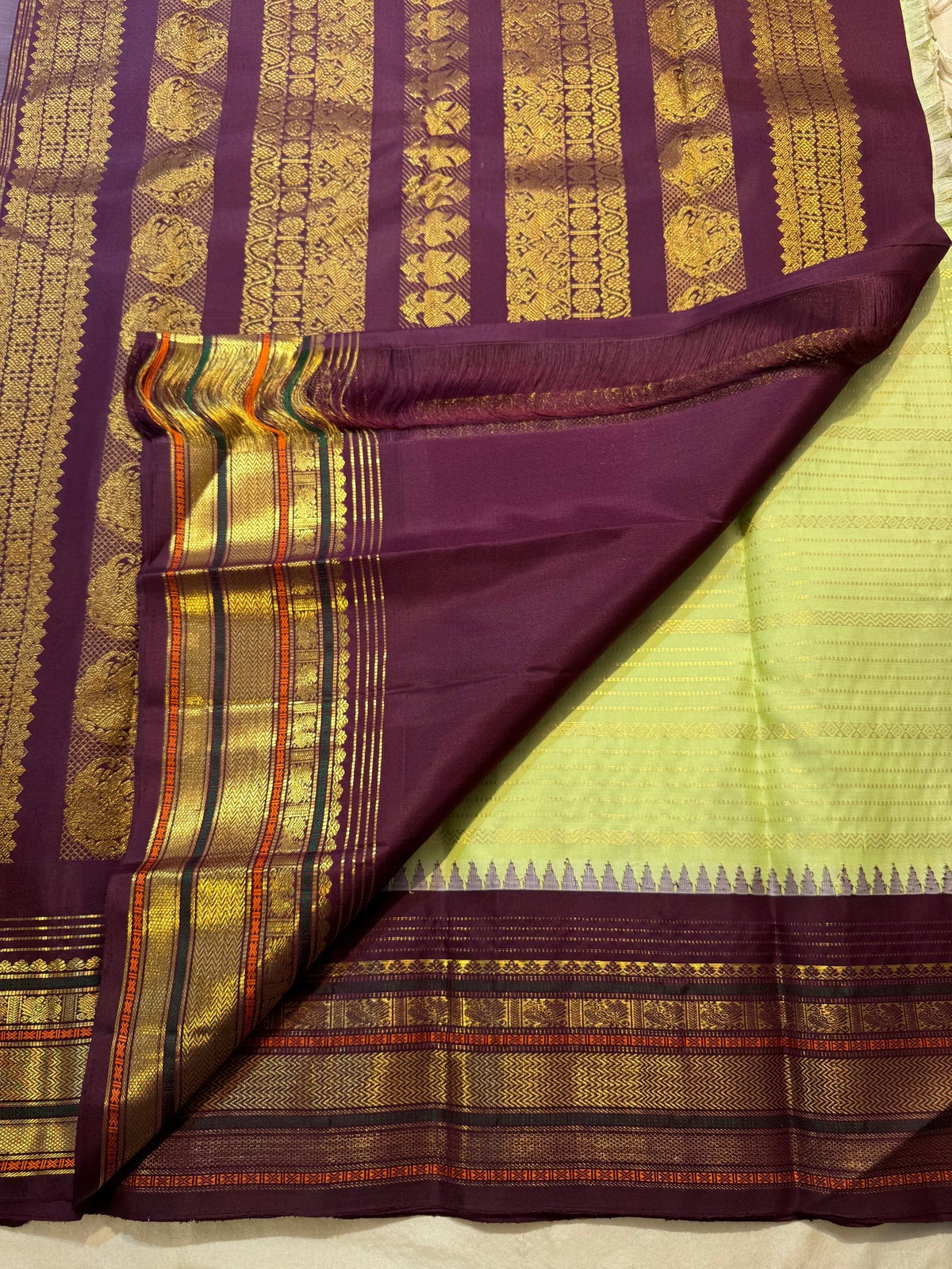 Close view of fine classic-gold zari lines across pistachio-green Kanchipuram silk.