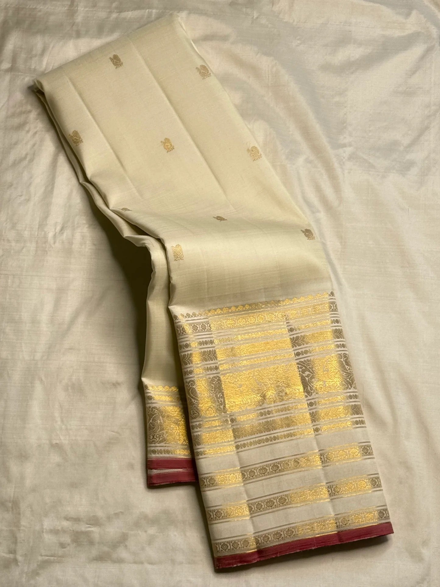 Folded ivory pure silk Kanchipuram Butta saree showing zari buttas and border