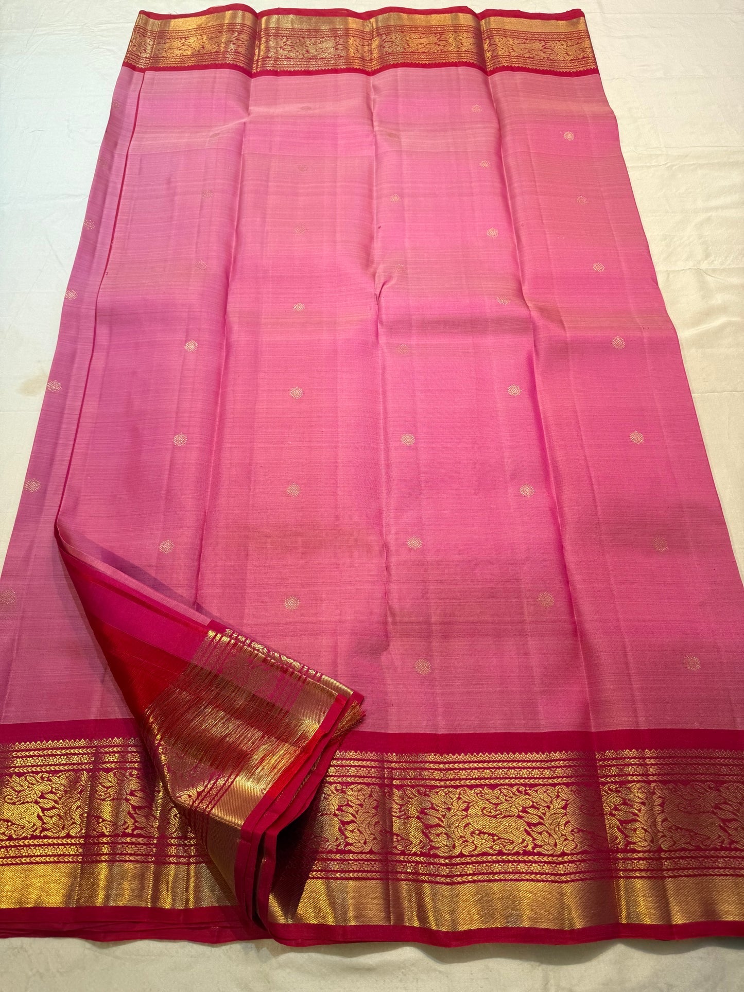 Rose pink Kanjeevaram Korvai silk saree folded, showing raspberry-red border detail