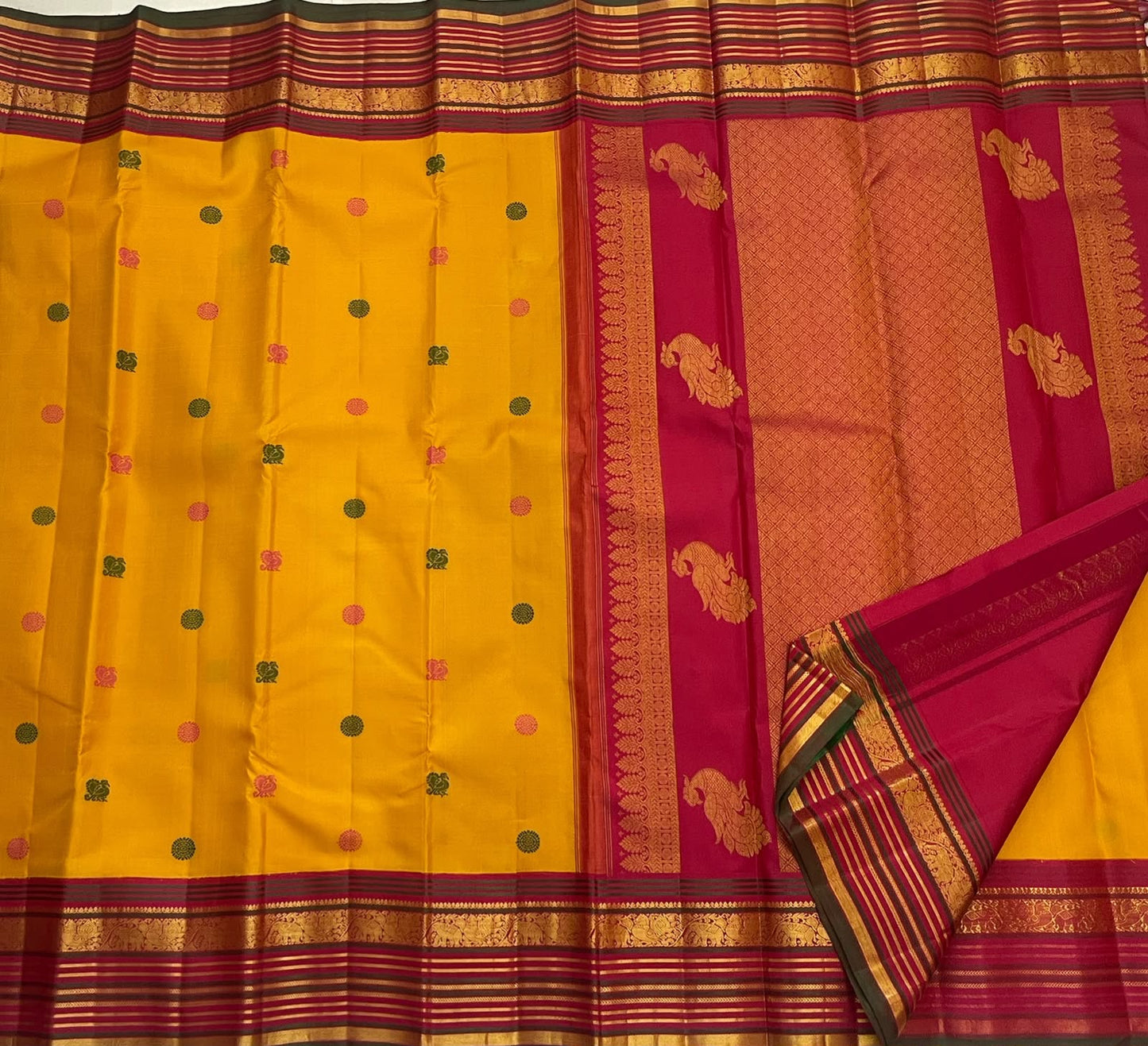 Raspberry pink zari border detail on the golden turmeric pure silk Kanchipuram saree.