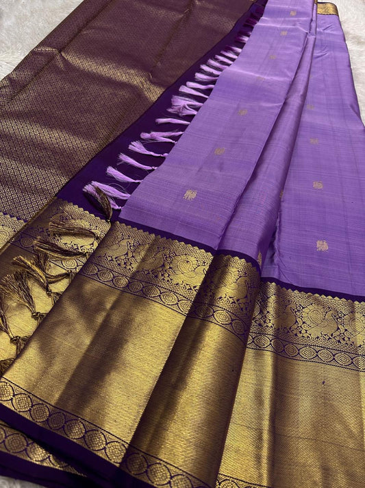 Purple Kanchipuram silk saree showing antique gold zari border detail and pallu tassels laid flat