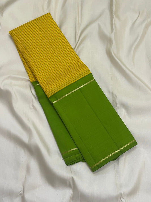 Green Pure Kanchipuram silk saree folded with yellow checked panel and slim zari woven border