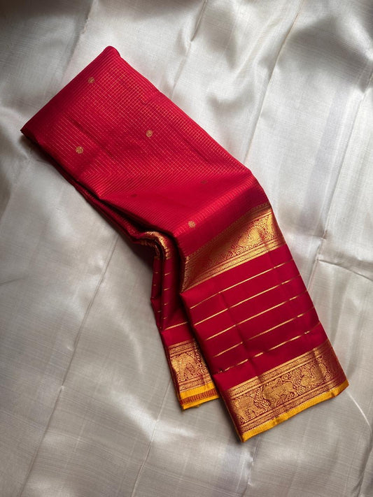 Deep red Kanchipuram silk saree with subtle zari kattam lines and antique gold zari border, angled fold detail
