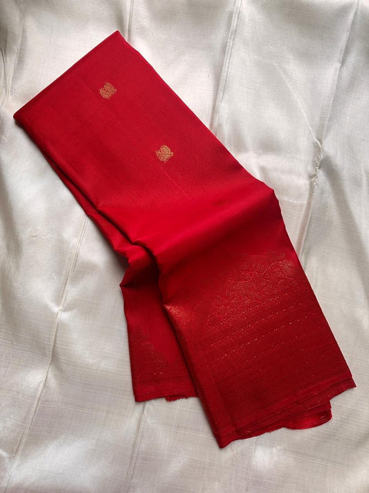 Stacked pure Kanchipuram silk sarees showing red, green, purple, and maroon shades with zari butta work