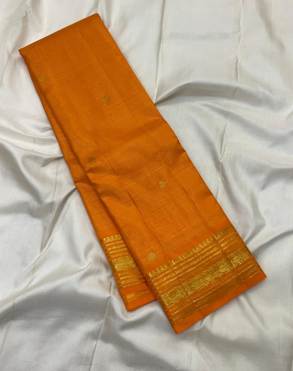 Saffron Orange silk saree with spaced warm gold zari buttas.