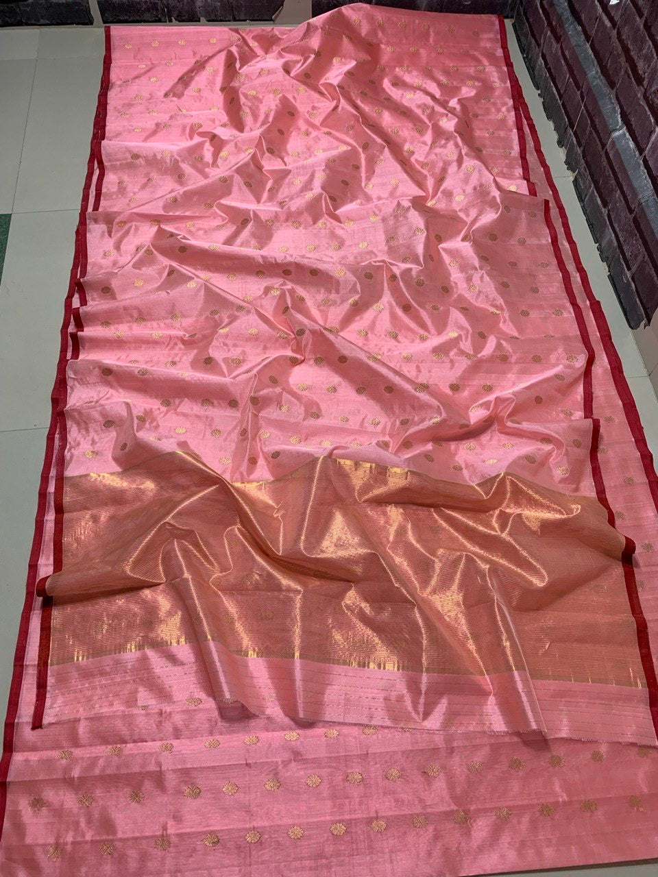 Soft pink body close-up showing gold coin-disc motifs