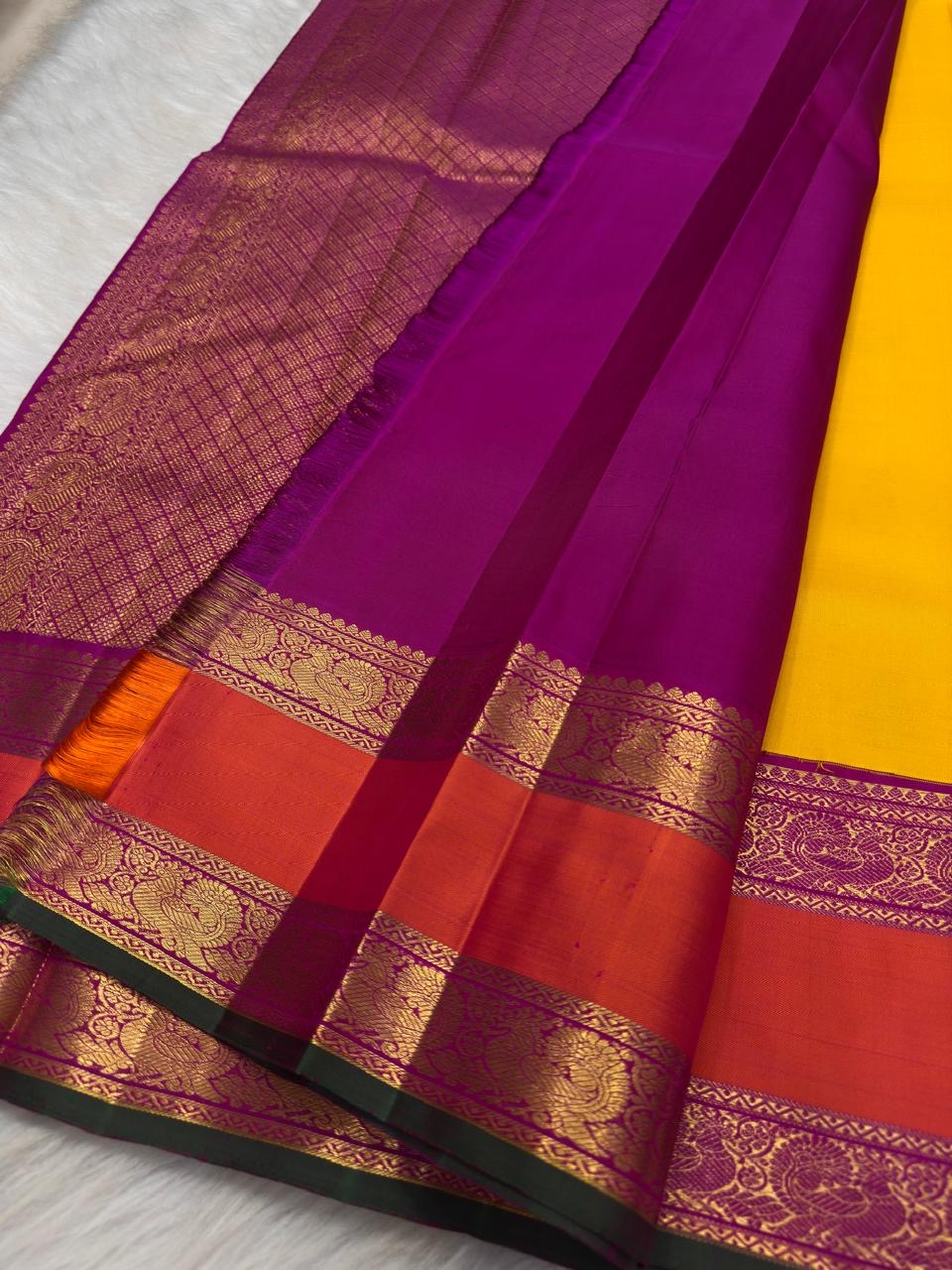 Close view of spaced Mayil gold-zari buttas across the sunflower-yellow pure silk body.