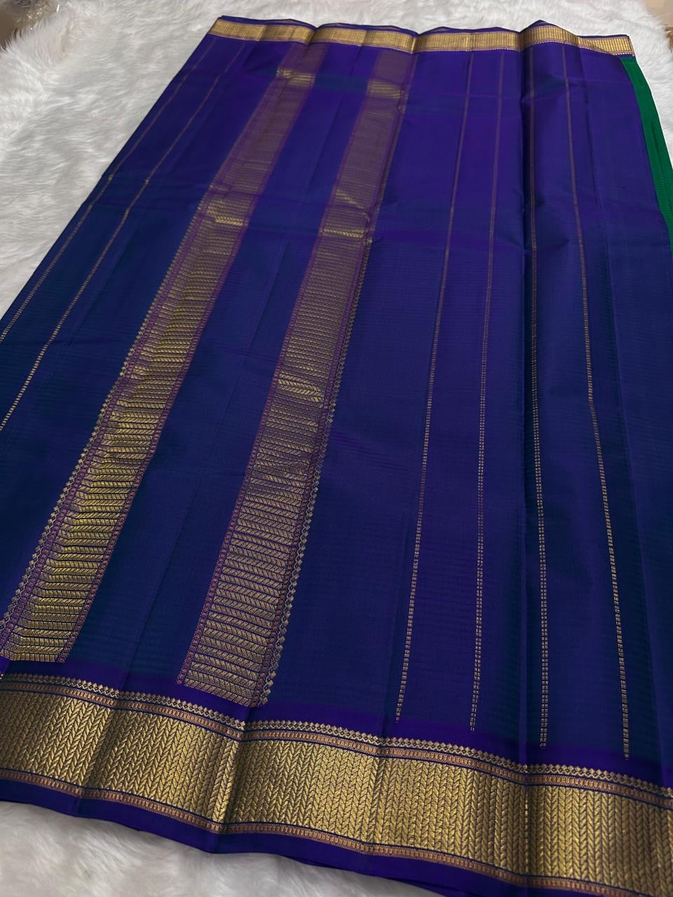 Emerald Green and Neelam Violet-Blue lightweight Kanchipuram silk saree, geometric gold zari border and patterned violet-blue pallu; pallu folds
