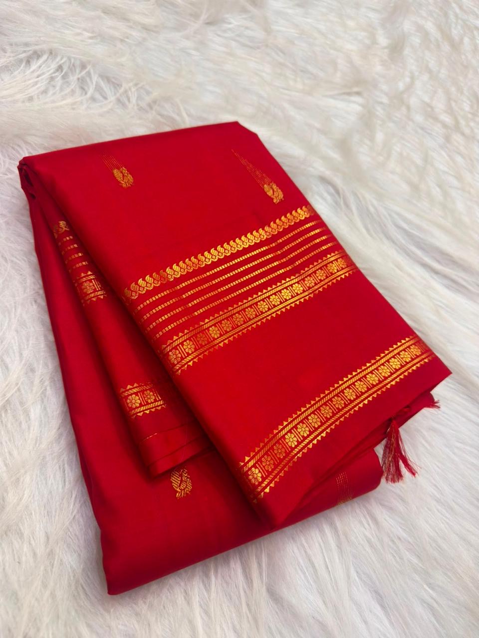 Vivid red Kanchipuram silk body with individually spaced classic-gold zari buttas across an open field.