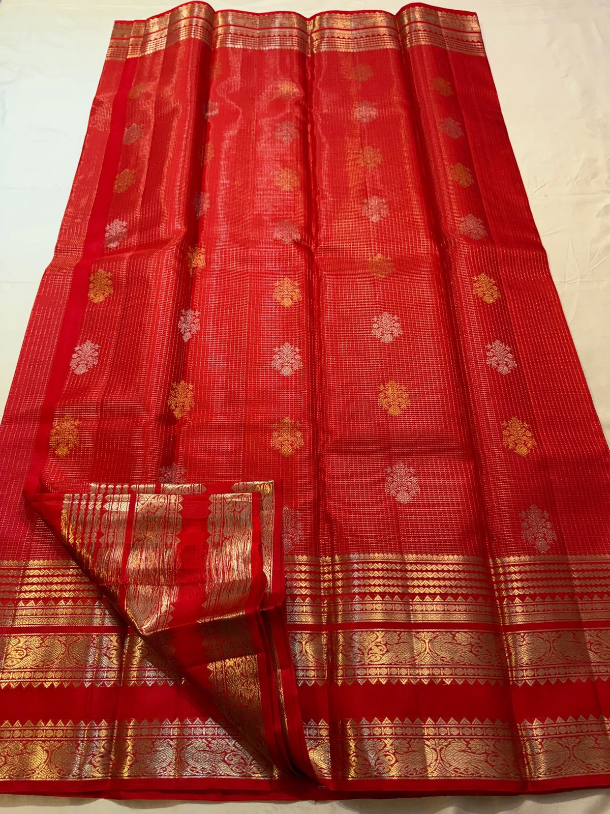 Handwoven vermilion silk body showing fine gold zari Kattam lines and scattered woven motifs.