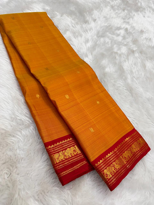 Pure silk Kanchipuram saree in mango mambazham yellow showing body texture and red antique gold zari border
