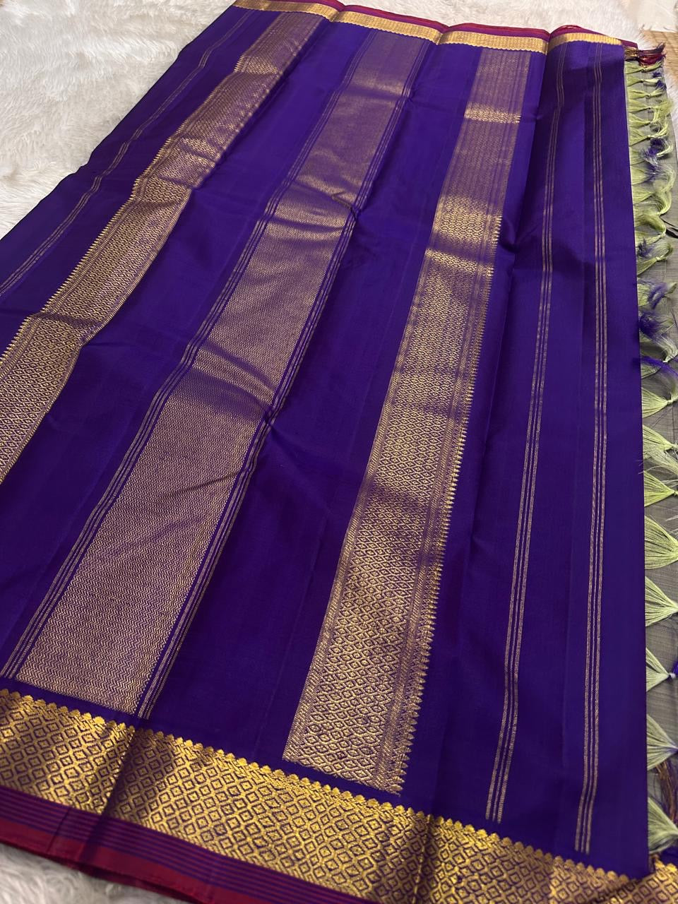 Varnam – Dove Tail Gray & Purple, a Kanchipuram silk saree where elegance meets bold expression. The soft dove tail gray base is adorned with vibrant magenta checks,Framed by a rich purple zari border and finished with an intricate contrast pallu