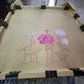 Close up of brush applying pink lotus design on silk blouse