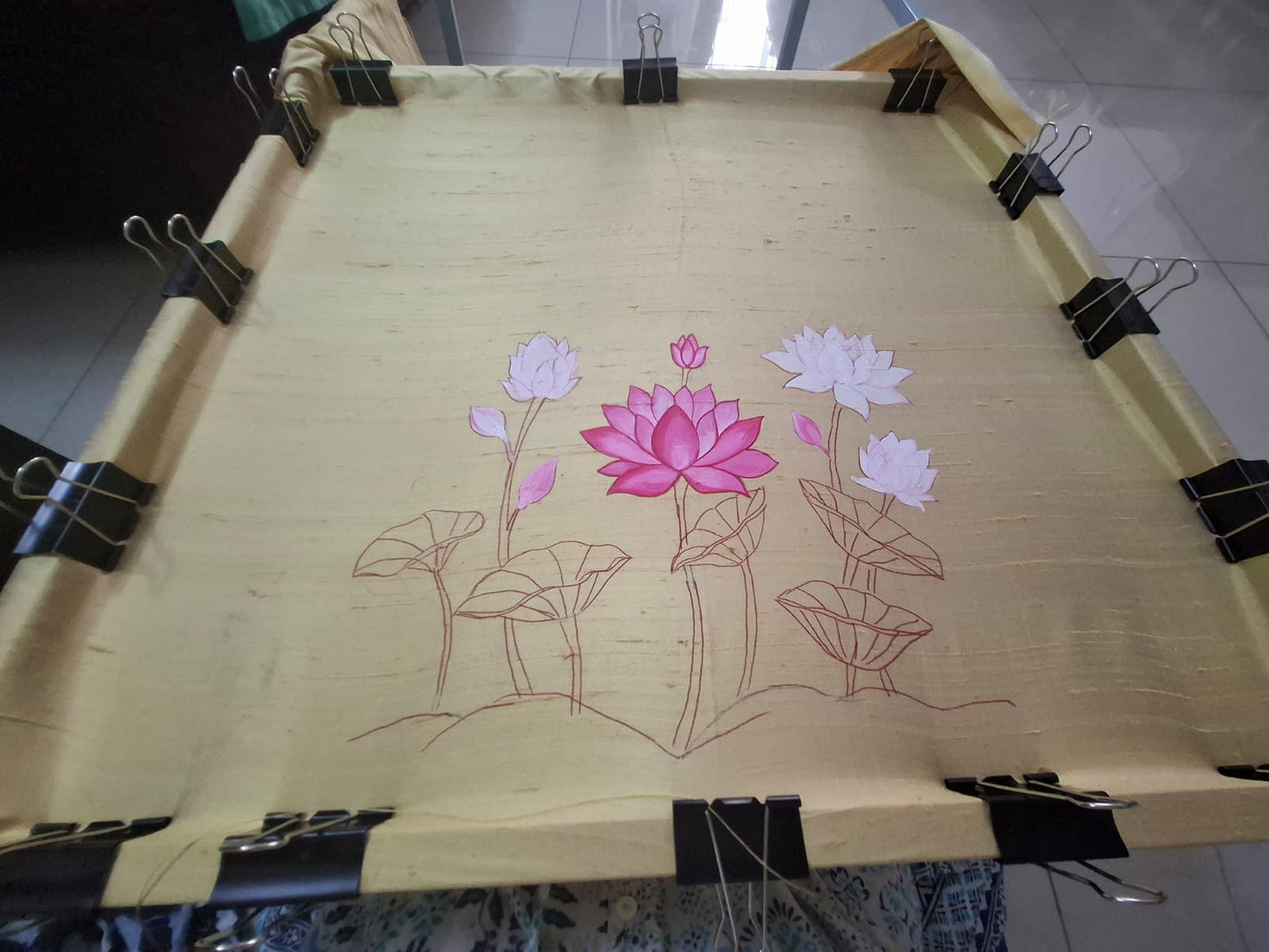 Close up of brush applying pink lotus design on silk blouse