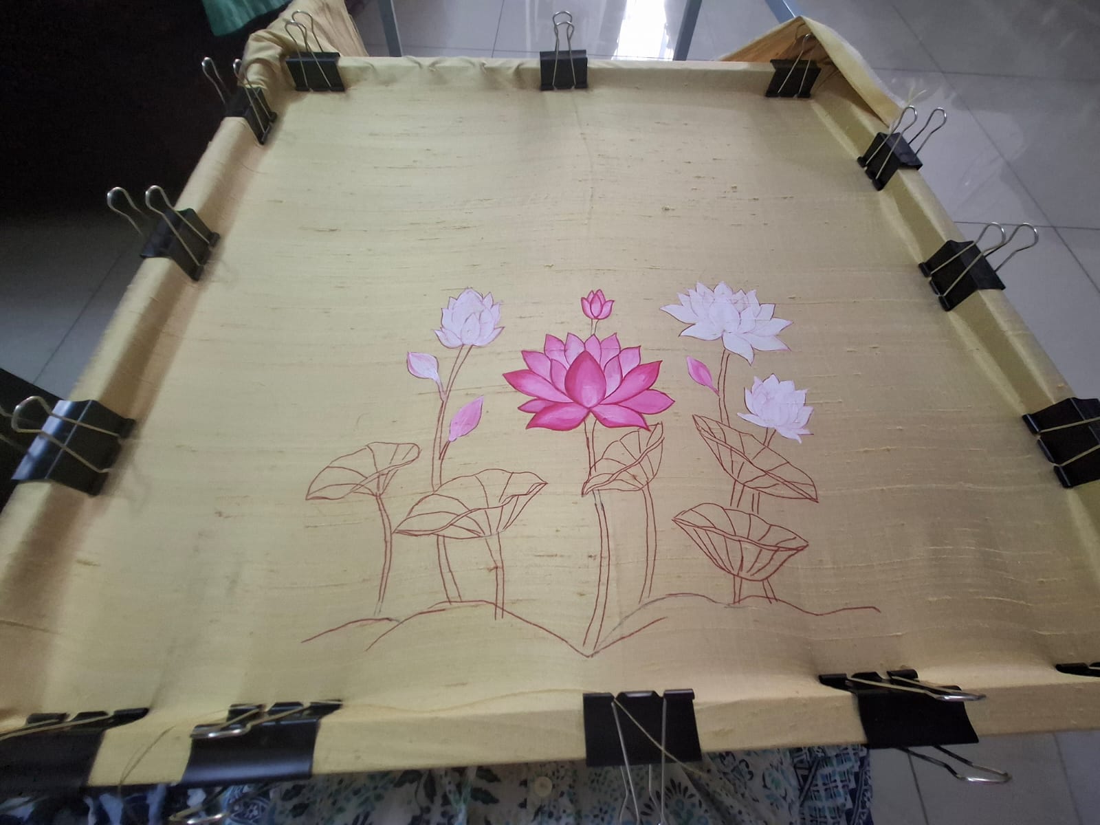 Close up of brush applying pink lotus design on silk blouse