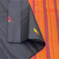 Black Pure Kanchipuram Silk Saree fabric with a yellow bird motif draped beside an orange striped pallu with pink border.