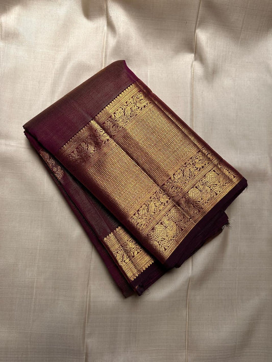 Varnika – Handwoven Kanchipuram Silk Saree in Plum Wine
A regal plum Kanchipuram silk saree adorned with gold zari paisleys and Gandaberunda motifs